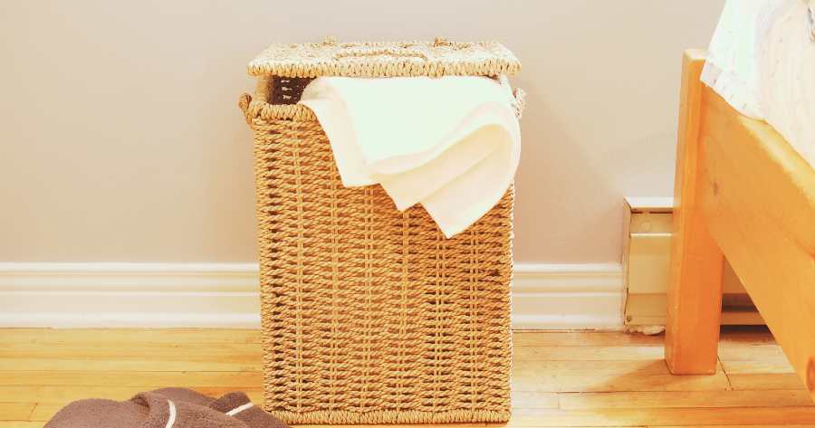 laundry hamper beside a bed