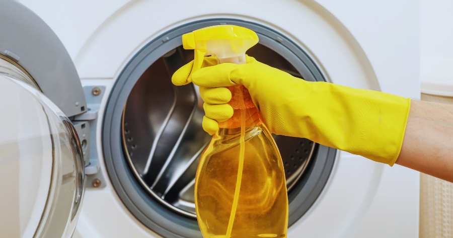 person wearing gloves cleaning a washing machine with a cleaner