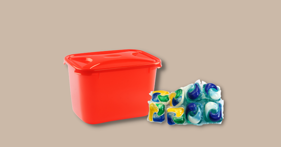 orange canister with lid and laundry detergent pods against brown background