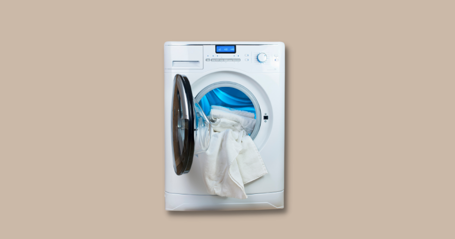 white towels hanging in the opening of a front load washing machine against brown background