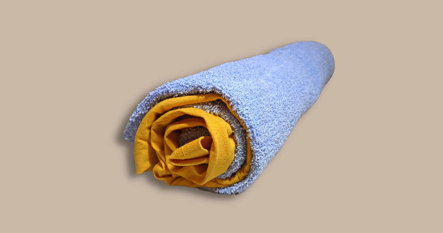 yellow t-shirt rolled into a blue towel like a log